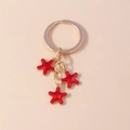 Detail van gouden sleutelhanger met drie rode zeesterren voorzien van witte stippen - Rood