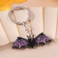 Dettaglio portachiavi a forma di pipistrello in metallo nero e ali viola per zaino - Pipistrello