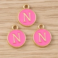 Detailed macro view of pink enamel letter N round pendants with golden metal frame - Letter N / 10 Pieces Pack