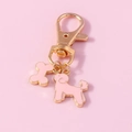 Close-up of golden lobster clasp with cute pink enamel dog and bone charms for keychains - Pink