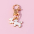 Detail of cute gold-edged dog and bone charms on a poodle keychain accessory - White