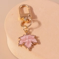 Vue détaillée du pendentif feuille d'érable rose avec fermoir doré sur une pierre - Rose