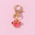 Detailopname van een gouden metalen sleutelhanger met een schattige roze kattenpoot hanger - Rood
