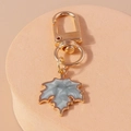 Vue détaillée du porte-clés feuille d'érable doré avec incrustation en marbre bleu - Gris