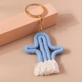 Détail du porte-clés cactus tricoté bleu clair fait main avec glands blancs et anneau doré - Bleu