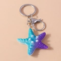 Dettaglio portachiavi a stella marina in resina sfumata blu-viola con perle bianche - Viola