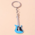 Detailansicht des himmelblauen Gitarren Schlüsselanhängers mit silbernen Saiten auf Beige - Blau