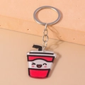 Détail d'un porte-clés tasse de boisson dessin animé avec visage souriant et anneau argent - Thé au lait
