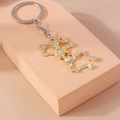 Close-up of a gold skeleton keychain accessory for backpacks on a pink pedestal - Gold