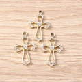 Detailansicht hohler Strass-Kreuzanhänger für DIY-Schmuck auf einer Holzoberfläche - Gold