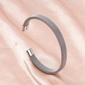 Brazalete abierto de malla plateada en acero inoxidable sobre fondo de satén rosa - Color Acero