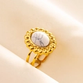 Gros plan d'une bague en acier doré avec turquoise marbrée blanche et serti de pétales - Base Or Pierre Blanche