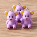Detailed macro view of three lavender resin bear charms with metal hooks on wooden background - Purple