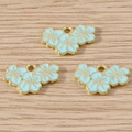 Detailed macro view of three light blue enamel flower charms on rustic wood surface - 10 Pieces Pack / Blue (YD216)