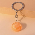 Dettaglio macro di un portachiavi a sfera di cristallo arancione con glitter e anello argento - Arancione