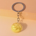 Macro detail of a yellow vortex texture pendant on a silver keychain over a stepped background - Yellow
