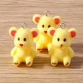 Close-up of cute yellow resin bear charms with red ear details and metal rings - Yellow