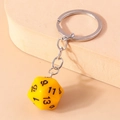 Detail of creative yellow D20 dice keychain with silver metal chain and black numbers - Black and Yellow