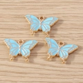 Vue détaillée de trois breloques papillons bleu clair avec cadres en alliage doré sur bois - Lot de 10 / Bleu