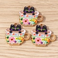 Vue macro de trois breloques en émail de chat noir dans une tasse à fleurs sur bois - Lot de 10 / Noir