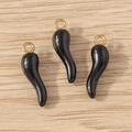 Close-up of black cornicello charms with gold rings on a natural wood surface - 10 Pieces Pack / Black