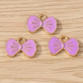 Detailansicht von drei lila Emaille-Schleifenanhängern mit Goldrand für DIY-Schmuck - 10er Pack / Lila