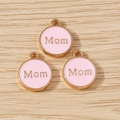 Close-up of pink enamel Mom charms with gold-plated edges for DIY jewelry making - Pink