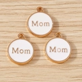 Detailed close-up of circular Mom charms with white enamel and golden alloy finish - White