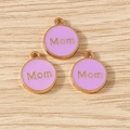 Detailed close-up of lavender enamel Mom charms with golden plating on wooden surface - Purple