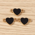 Dettaglio di tre connettori a cuore in smalto nero con montatura dorata per gioielli DIY - Nero
