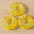 Close-up of yellow resin swim ring pendants with cartoon motifs for DIY jewelry - 5 Pieces / Yellow