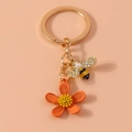Dettaglio del portachiavi ape dorata con perle e ciondolo a forma di fiore rosso - Arancione