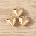 Drei goldene Herzanhänger mit Ringen für DIY-Schmuck auf hellem Holzgrund poliert - Gold