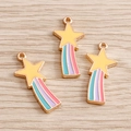 Close-up of enamel rainbow shooting star charms on a light wood background for DIY - Pink