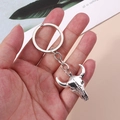 Detailed shot of a silver vintage bull skull keychain with metal ring for backpacks - Bull Head