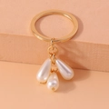 Detail of gold keyring with three white teardrop pearl pendants on textured stand - Triple Drop Pearl Style