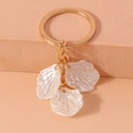 Dettaglio di un portachiavi con petali a conchiglia, anello dorato e finitura perlata - Stile Perlaceo Triplo Petalo / Conchiglia