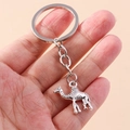 Macro detail of retro silver metal camel keychain held in hand for scale - Camel