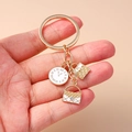Llavero dorado con reloj, colgante de bolso acolchado y accesorio sobre la mano - Blanco
