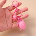 Detail of pink resin turtle keychain set with lobster clasp and metal ring hand-held - Pink