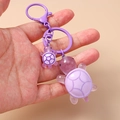 Close-up of cute purple resin turtle keychain with translucent jelly texture and metal clip - Purple