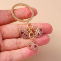 Close-up of golden keychain featuring three linked evil eye pendants with pink crystals - Pink Eye
