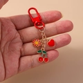 Llavero de moda con cerezas rojas, corazón y flor para bolsos y mochilas - Cereza