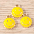 Close-up of three yellow enamel smiley face charms on a light wood background - 10 Pieces Pack / Yellow