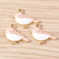 Detailed macro of three pink and white enamel bird pendants on light wood surface - Bird Charm (YD1719) / 10 Pieces Pack / Pink