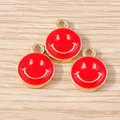Close-up of three red enamel smiley face charms with gold trim on wooden background - 10 Pieces Pack / Red