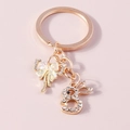 Golden bunny keychain with crystal bow and iridescent accents on pink background - Gold Bowknot Bunny Style (YZ421)