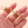 Détail d'un porte-clés à double croix dorée avec finition polie et mousqueton - Doré