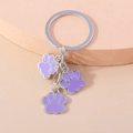Porte-clés en métal argenté avec trois breloques pattes en émail violet sur support - Violet