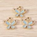 Dettaglio macro di tre ciondoli a farfalla in smalto azzurro con strass bianchi intarsiati - Farfalla Blu (YD1695jinlan) / Confezione da 10 / Oro